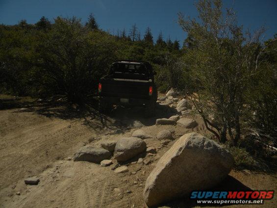 Black pickup truck driving on a rocky, dirt path