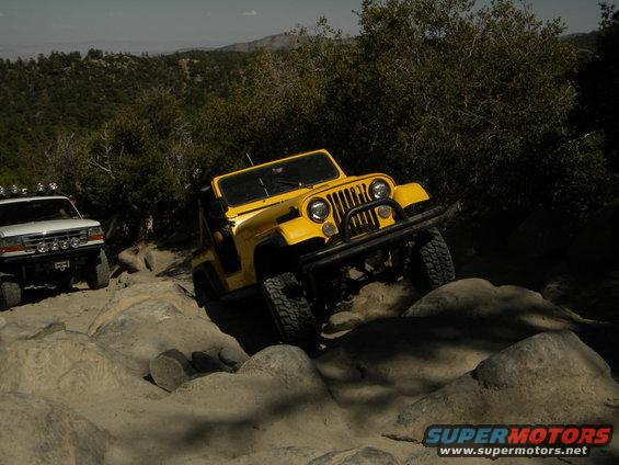 Yellow Jeep Wrangler navigating rocky terrain