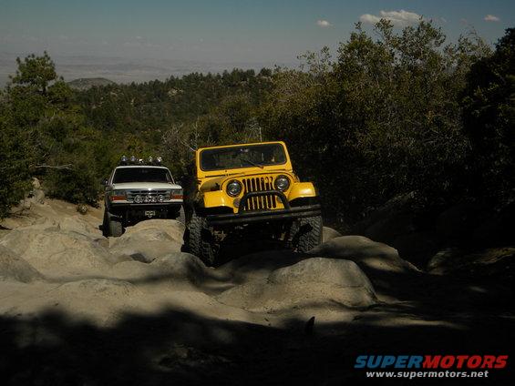 Yellow Jeep and white SUV driving on rocks off-road