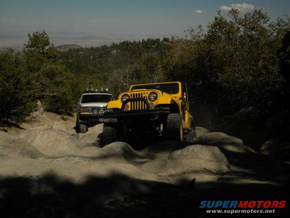 Yellow Jeep CJ and white Ford Bronco navigating rocky terrain off-road