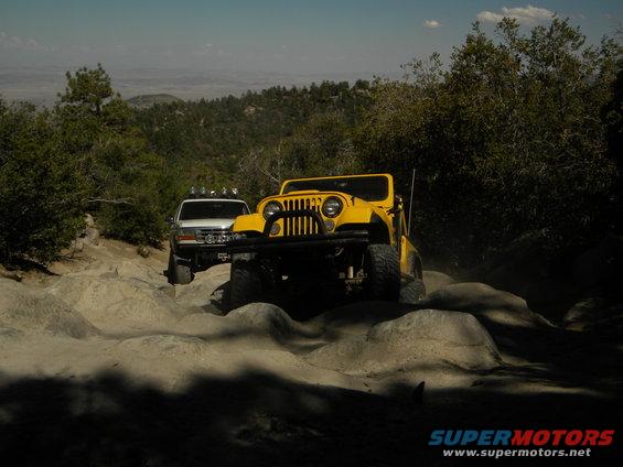 Yellow Jeep and white SUV navigate a rocky mountain trail