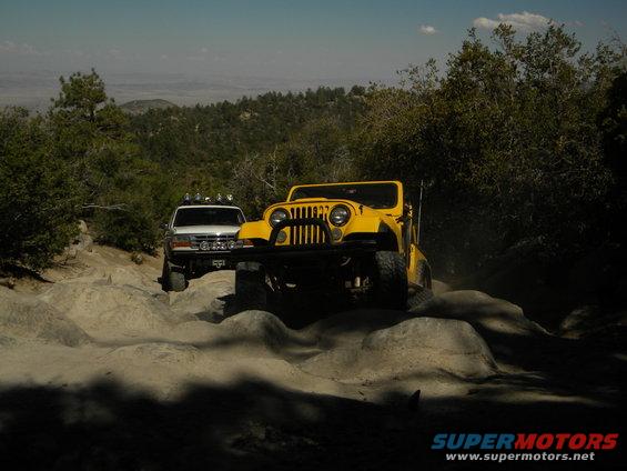 White Ford Bronco and yellow Jeep on rocky terrain