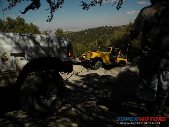 White SUV and yellow Jeep on rocky terrain