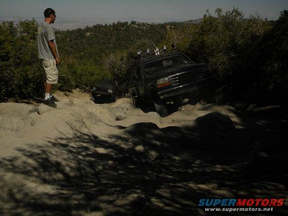 Black 1992 Ford Bronco off-roading on a rocky trail, front-right quarter view