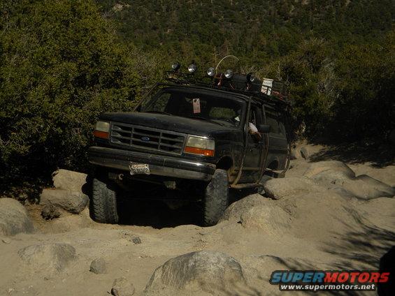 Black 1992 Ford Bronco driving over rocks on a trail