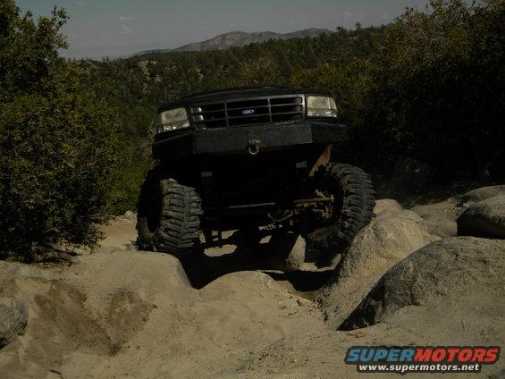 Black 1992 Ford Bronco on rocky terrain, front view, lifted suspension, large tires