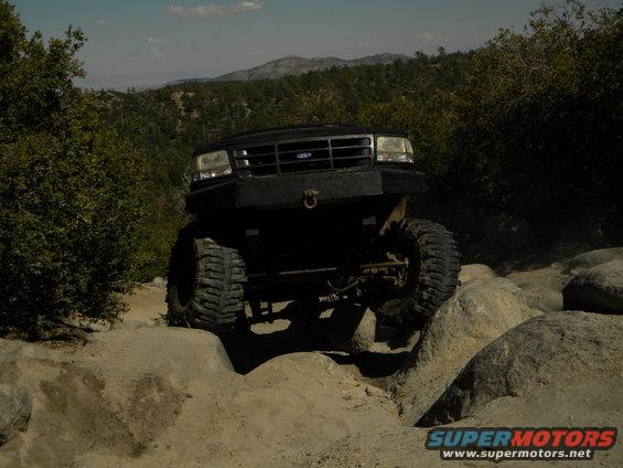 Black 1992 Ford Bronco with custom bumper navigating rocks