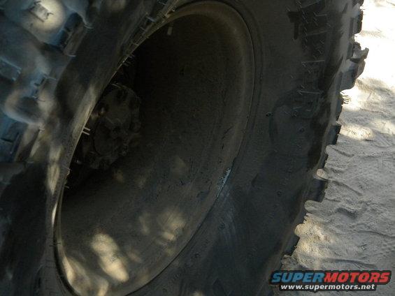 Close-up of a large off-road tire and wheel, showing tread detail and part of the hub