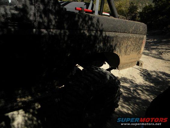 Muddy off-road truck with large tires, seen from the rear quarter
