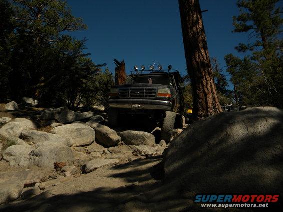 1992 Ford Bronco parked on a dirt path with trees and rocks