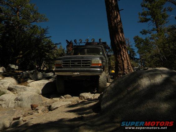 Ford F-Series truck on a rocky trail, front view. It has a roof rack with lights