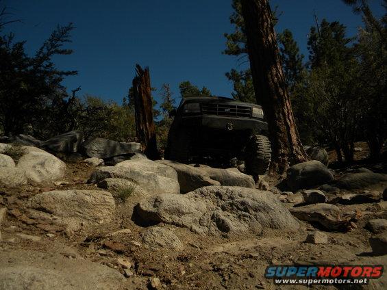 Black 1992 Ford Bronco driving over rocks on a trail