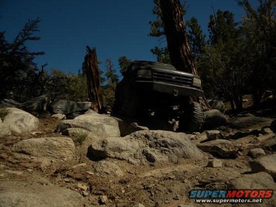 Dark 1992 Ford Bronco climbing over rocks on a trail