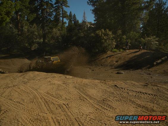 Yellow off-road vehicle splashing mud on a dirt track