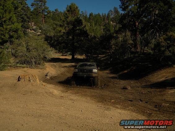1992 Ford Bronco driving through mud on an off-road trail