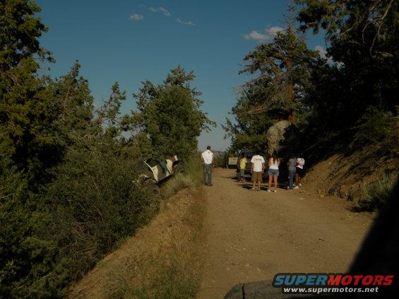 Off-road vehicles on a dirt road with people standing around