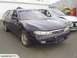 1993 Mazda MX-3 - A dark blue sedan is parked next to a heavily damaged silver car in an outdoor lot.