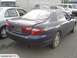 1993 Mazda MX-3 - A dark blue sedan is parked in a lot with other vehicles. The rear bumper shows damage.