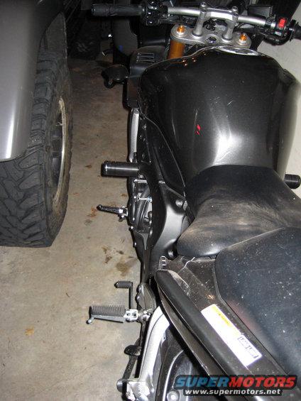 Black motorcycle parked next to a large tire, side view