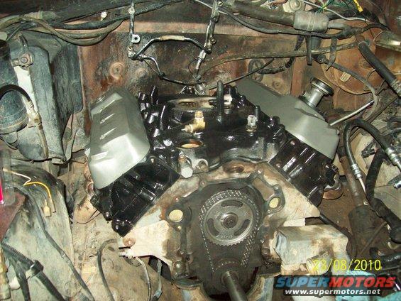 close-up of a V8 engine with timing chain exposed, wires and hoses visible