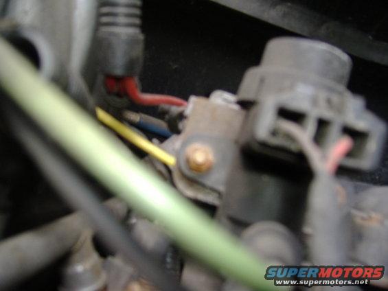 Close-up of engine wiring with red, yellow, and blue wires connected to a gray electrical component
