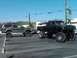 1986 Ford Bronco - A heavily modified black Ford F-Series truck, likely from the early 1990s, is parked next to a lifted green SUV.