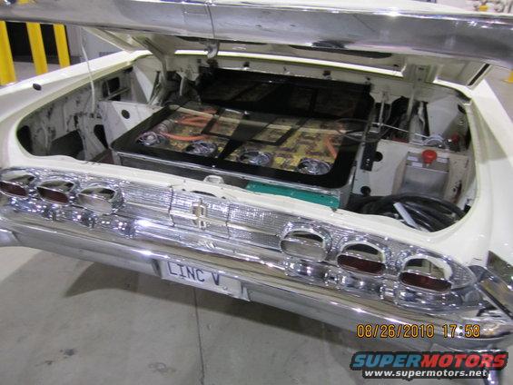 Trunk of a 1958 Lincoln Continental showing a custom audio setup with multiple speakers and amplifiers