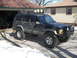 1988 Ford Bronco - This black Jeep Cherokee XJ features a roof rack with auxiliary lights and aggressive off-road tires.