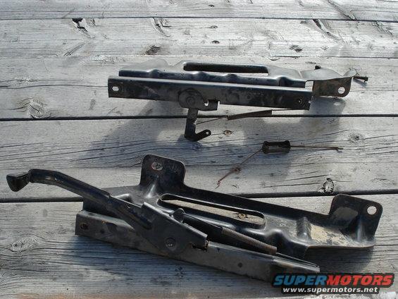 Black car jack and mounting bracket on wooden planks