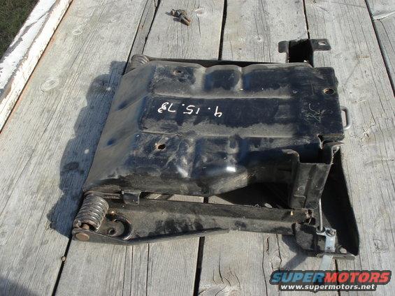 Black metal automotive part with springs, marked '4.15.79'