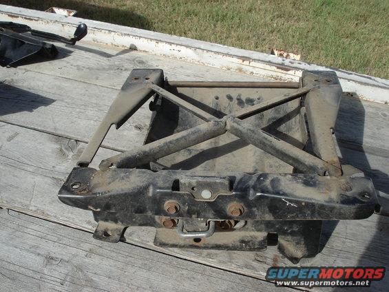 Black metal seat base with visible rust and wear, mounted on a wooden surface