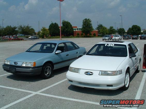 Light blue and white Ford Taurus sedans parked in a lot, one with a '130' sticker on the windshield