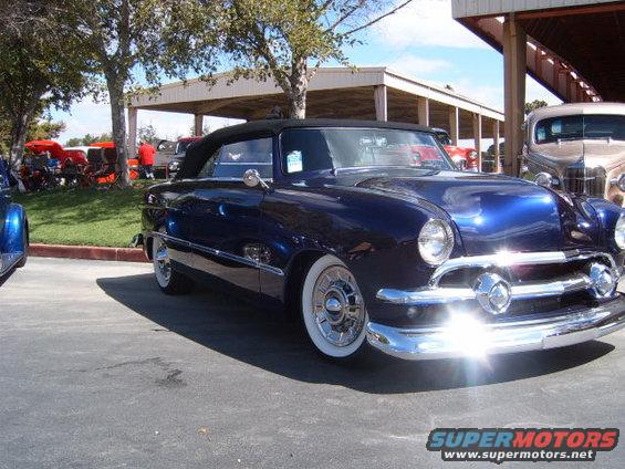 Dark blue convertible with whitewall tires and chrome grille parked outside