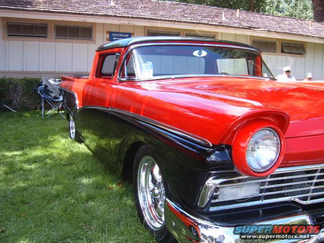 1956 Ford Fairlane pickup truck, red and black two-tone, chrome wheels, parked on grass