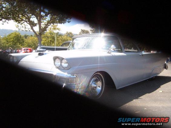 Gray 1957 Ford Fairlane, front quarter view, parked outside with trees and other cars in background