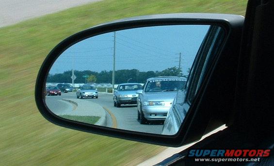 Several cars driving on a highway, viewed in a side mirror