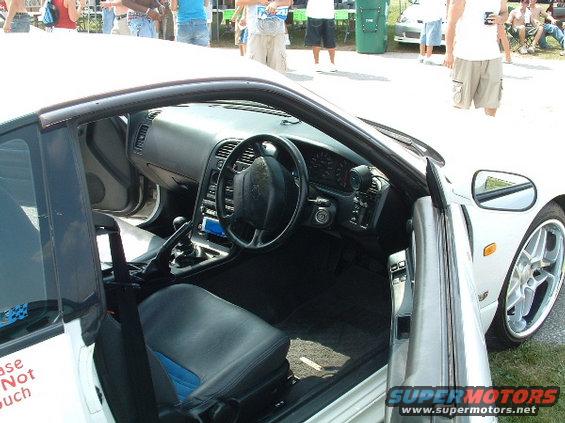 Interior of white sports car with blue accents on seats and a black steering wheel