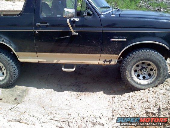 Side view of a black 1990 Ford Bronco with tan trim and 4x4 badging