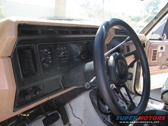 Dashboard and steering wheel of a truck, showing gauges and vents. Some wiring is visible below the dash