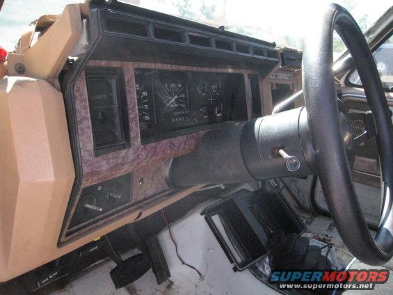 Dashboard interior with wood-grain trim, analog gauges, and a black steering wheel