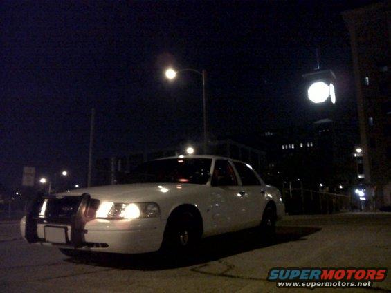 2003 Ford Crown Victoria police car parked on street at night, front grille guard visible