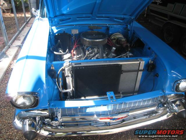 1957 Chevrolet Bel Air engine bay with V8 engine, chrome grille, and blue paint