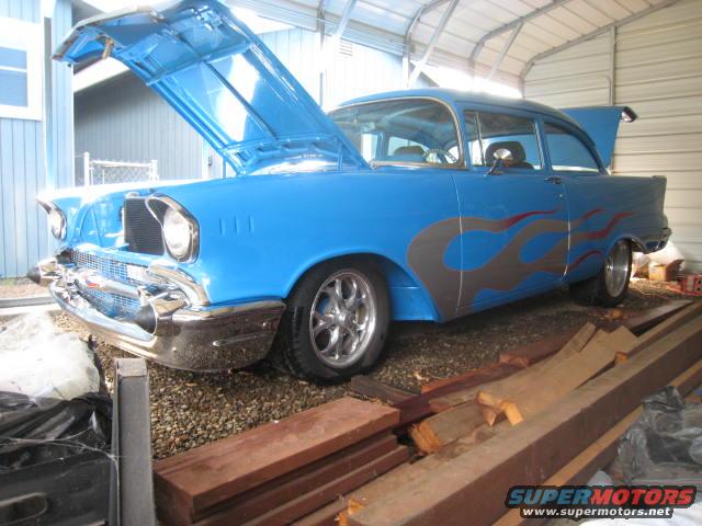 blue 1957 Chevrolet Bel Air with gray and red flames on the side, hood and trunk open