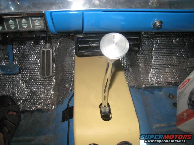 1957 Chevrolet Bel Air interior showing floor shifter, pedals, and dashboard controls. Insulation is visible on the floor and firewall
