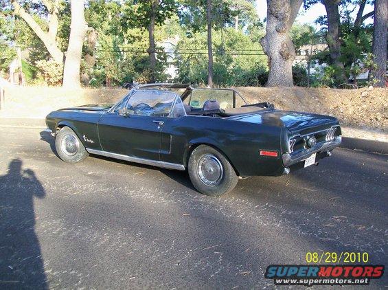 1968 Ford Mustang convertible, dark green, parked on asphalt. Shadow of photographer visible on left
