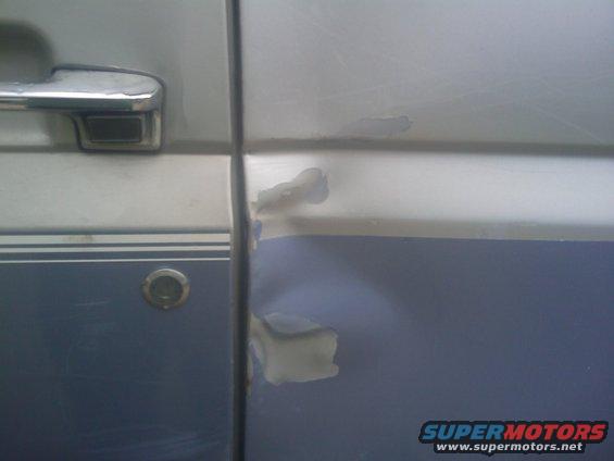 Dented and scraped two-tone blue and silver vehicle door with chrome handle