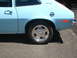 1972 Ford Pinto - Close-up of a light blue coupe's rear quarter panel, showing the fuel filler door and a chrome wheel.