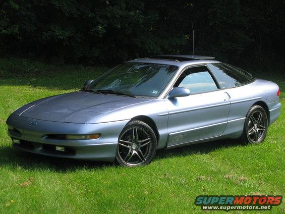 1994 Ford Probe GT, blue, parked on grass with trees in background