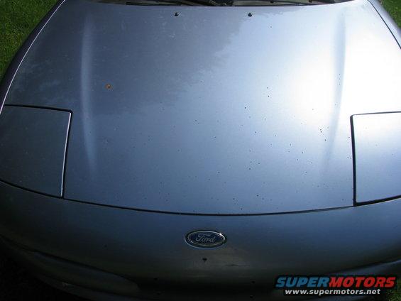 Silver car hood with pop-up headlights and a Ford emblem