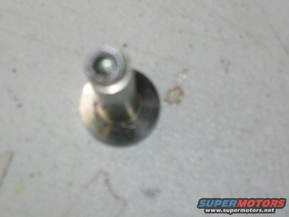 Metal bolt with a washer, on a light gray surface. Text "SUPERMOTORS www.supermotors.net" is visible in the lower right